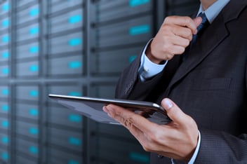 uomo con un tablet in mano e nello sfondo un data center